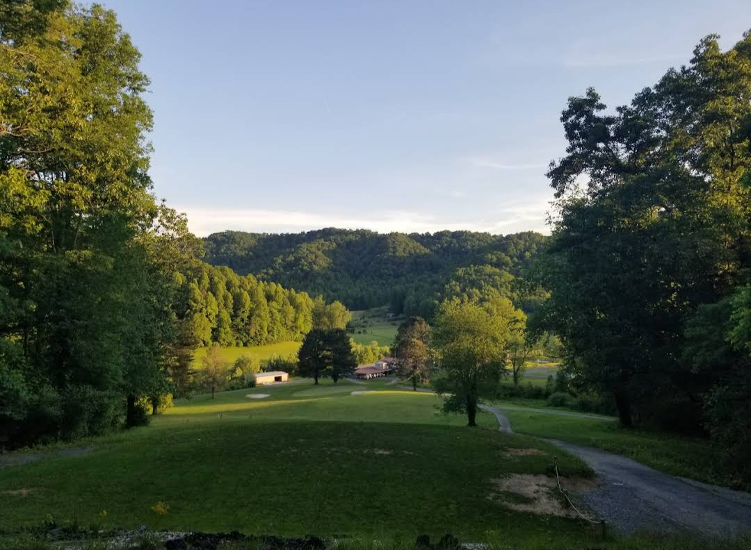 Sunlit Willowbrook fairway and clubhouse seen from an elevated tee box in summer