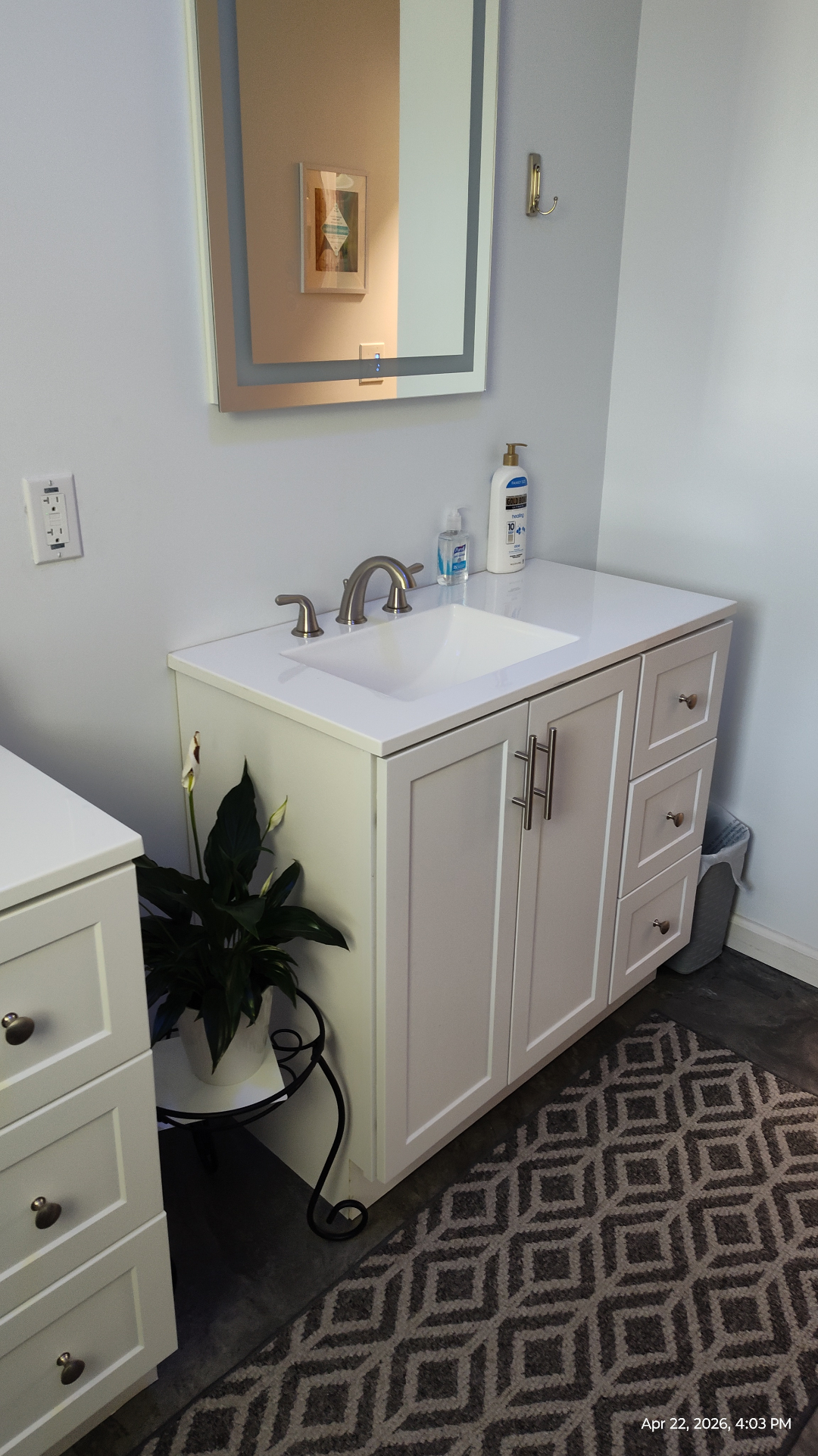 Bathroom vanity with quartz countertop and lit mirror